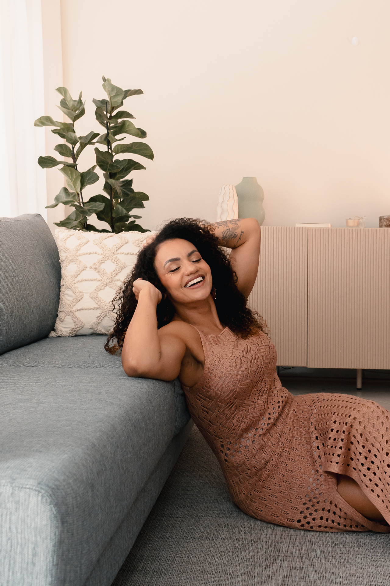 Paula sorrindo, sentada em um sofá